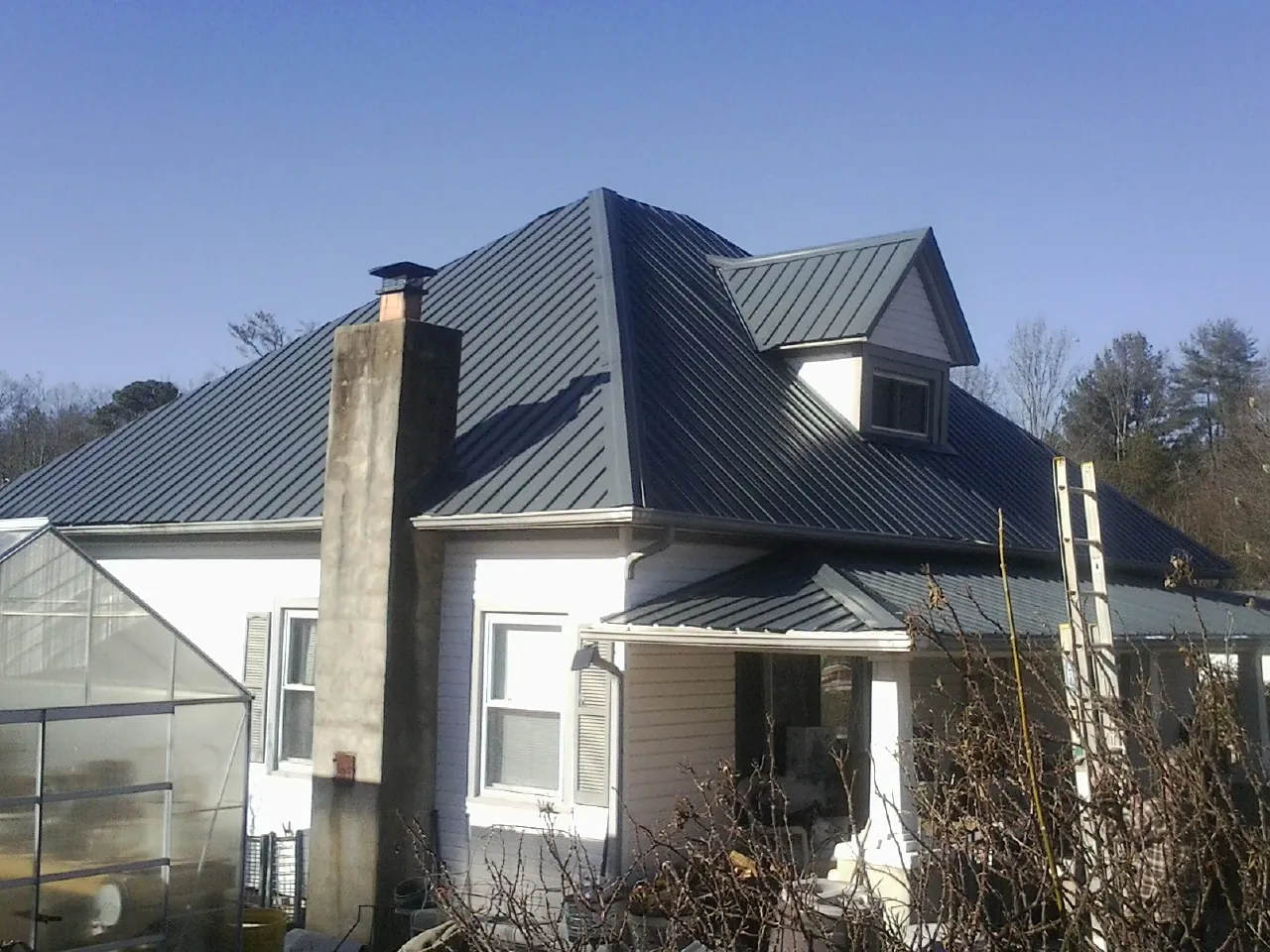 Dark blue standing seam metal roof on a white farmhouse with dormer — Slate & Tile Roof Repair by Roofing Brothers in Uxbridge