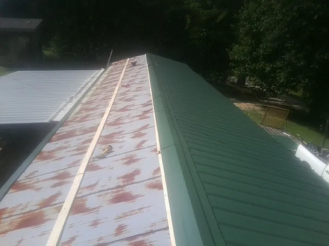 Old rusted panels beside newly installed green metal roofing — Wind Damage Roof Repair by Roofing Brothers in Uxbridge
