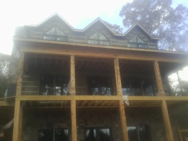 Dormers and porch framing on a large log home under construction — Roof Coating work by our crew in Uxbridge
