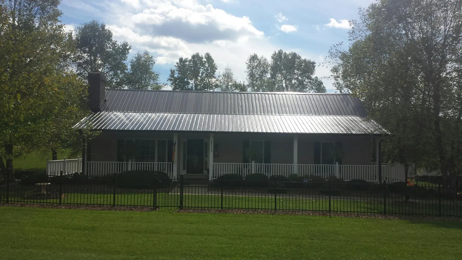 Gray metal roof on a brick ranch with a full width front porch — Gutter Guard Installation work by our crew in Uxbridge