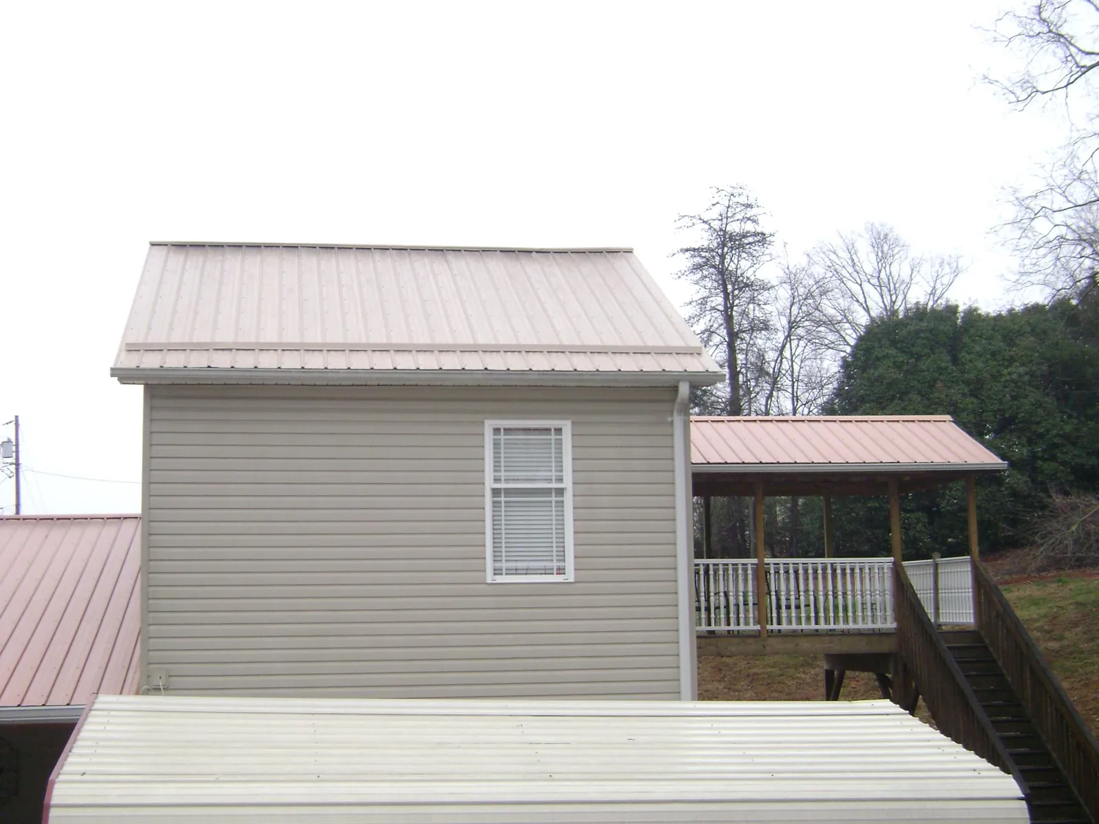 Tan metal roofs on a two story addition and attached porch, from a Roof Replacement job in Uxbridge