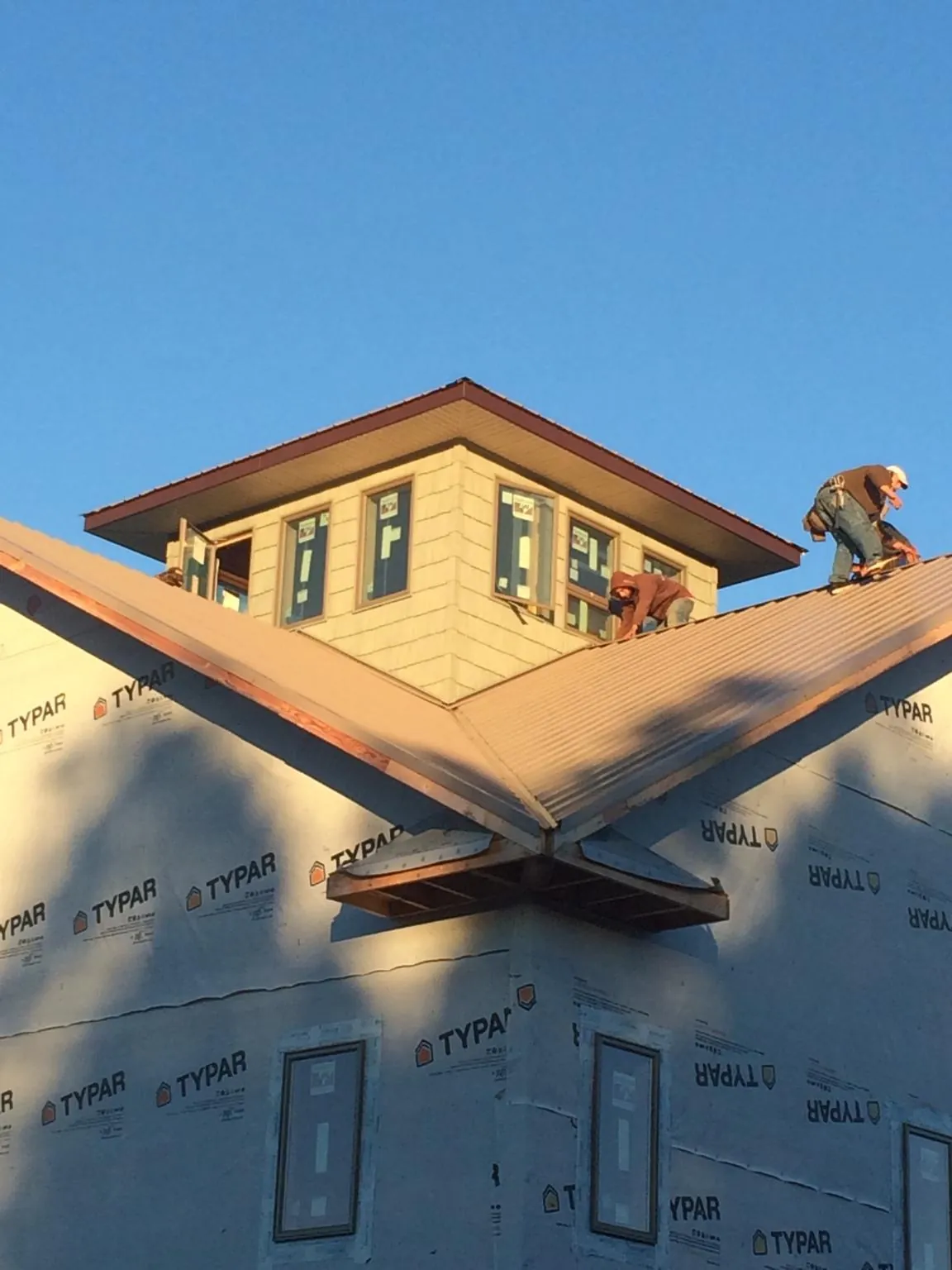 Roofers working around a rooftop cupola on a new metal roof at sunset — Roof Waterproofing in Uxbridge by Roofing Brothers